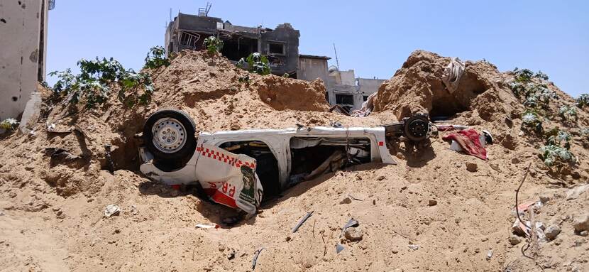 Een auto van hulpverleners onder het puin in Gaza